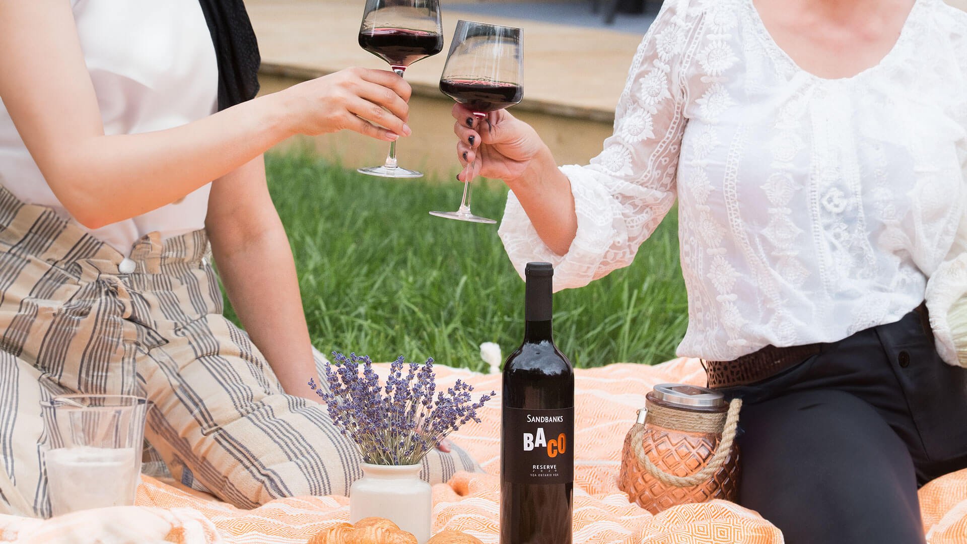 Couple enjoying a glass of Sandbanks Baco Reserve on a picnic date.